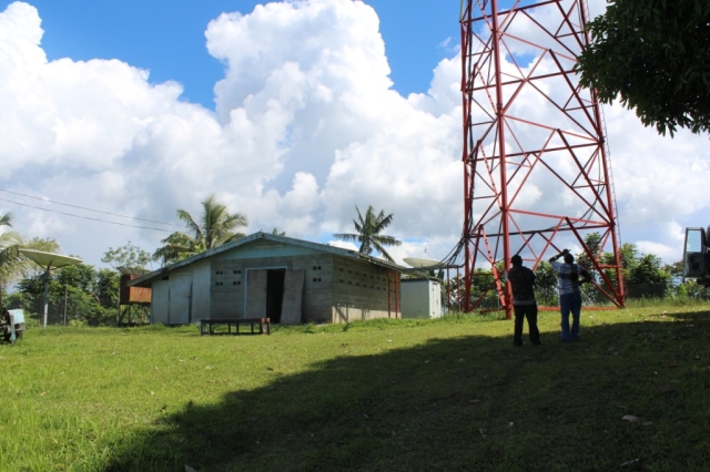 An image of two people looking up at a large antenna